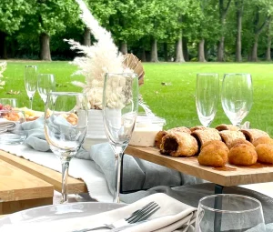 Melbourne event styling picnic setup gourmet food Elegant Melbourne picnic event styling with gourmet food platter, pastries, florals, and luxe tableware on a low timber table setting in the park.