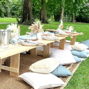 Boho style picnic table hire setup in a Melbourne park with wooden tables, cushions, and neutral-toned decor.